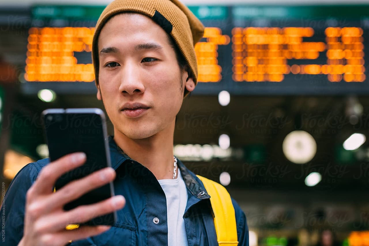 Man bekijkt telefoon op treinstation in het buitenland